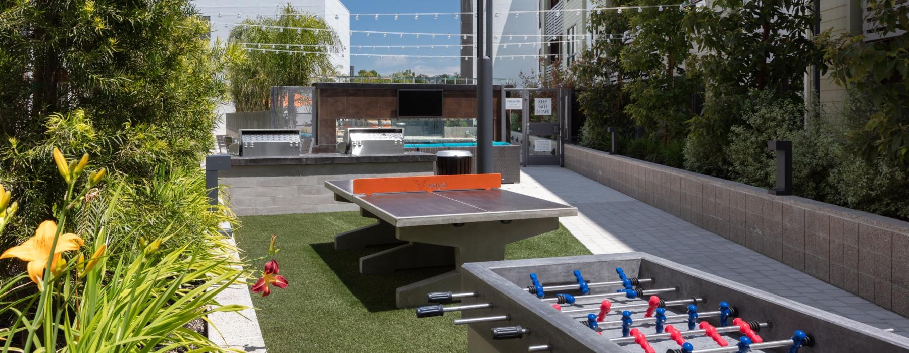 Outdoor game lounge with view of ping pong and foosball tables at Vaya pet-friendly apartments in Walnut Creek, CA